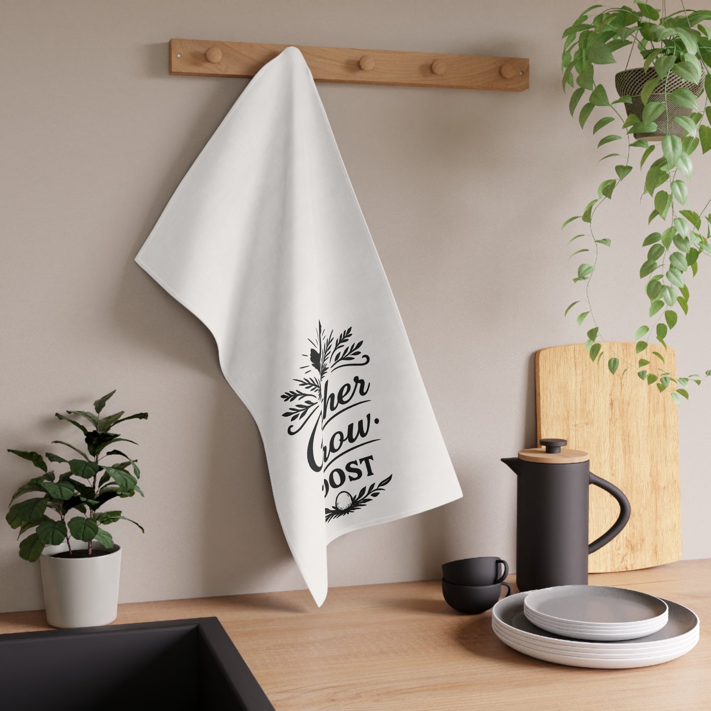 White towel with black text hanging on a wooden rack in a kitchen setting.