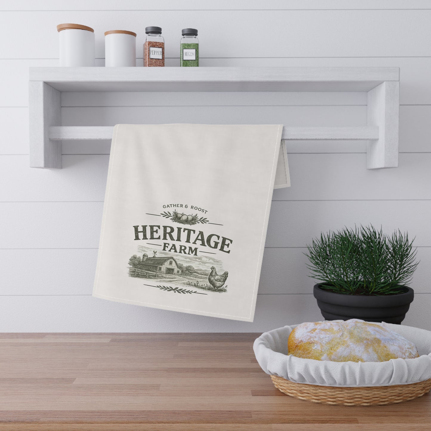 Kitchen towel with 'Heritage Farm' design hanging on a shelf above a wooden counter.